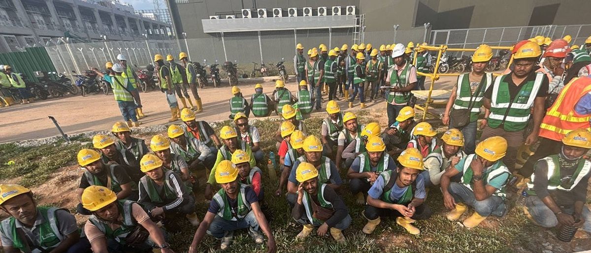 Site crew in helmets and safety vests gathered for a morning briefing